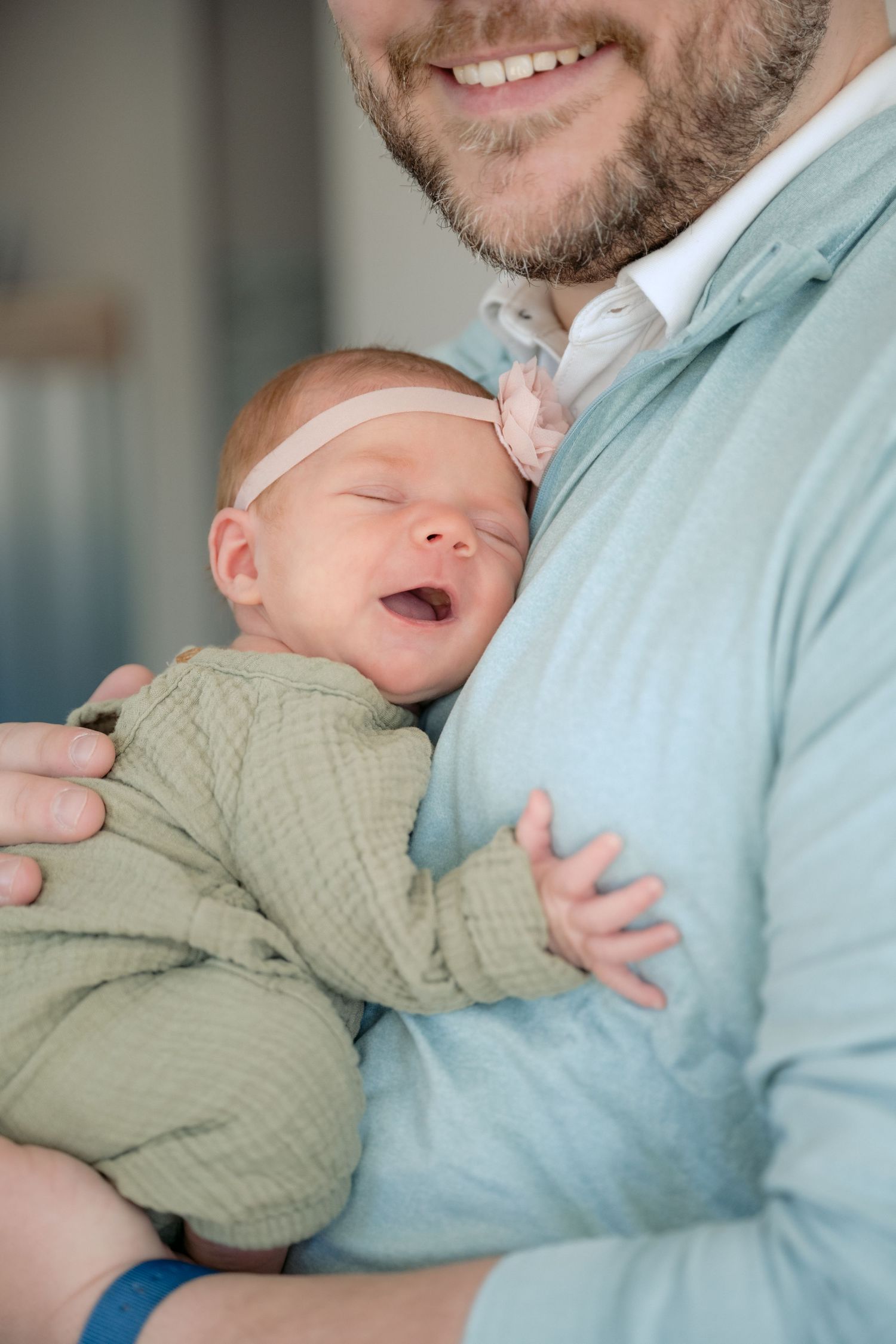 newborn baby smiles while snuggling with dad during in home lifestyle newborn session in lake elmo, mn