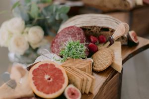 Elegant charcuterie board with salami, crackers, figs, grapefruit, strawberries, and microgreens on rustic wood.