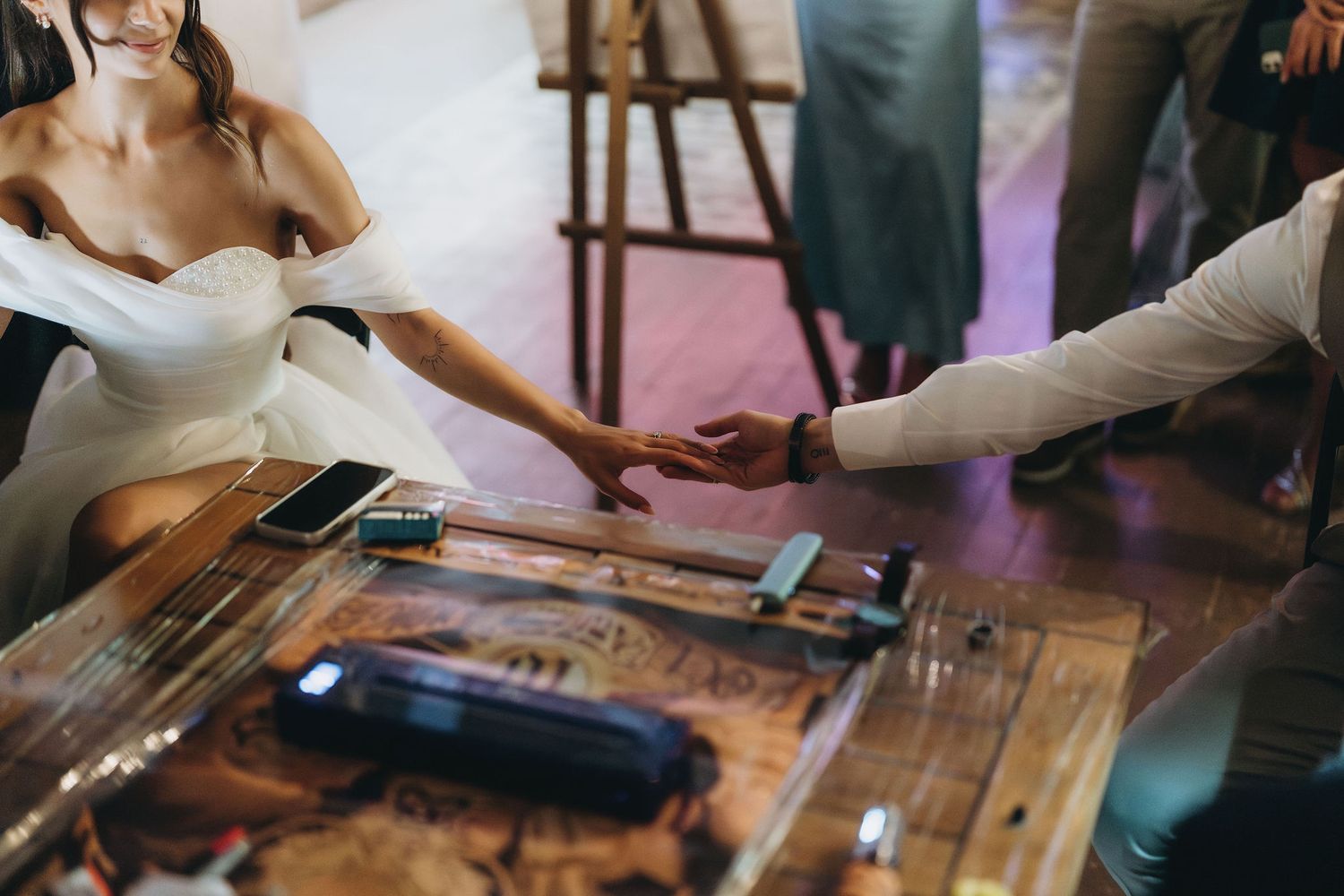 Bride and groom exchanging rings at a rustic wooden table with tools during a wedding ring ceremony.