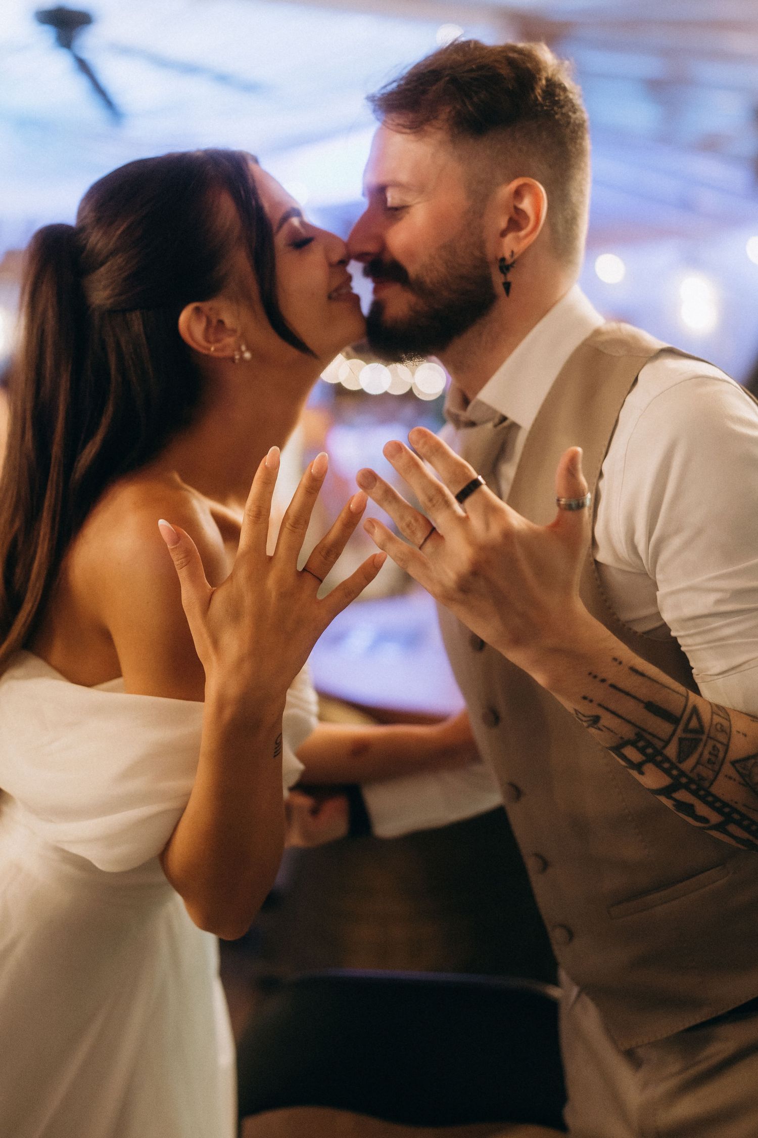 Newlywed couple sharing a kiss while showing off their wedding rings during their first dance.