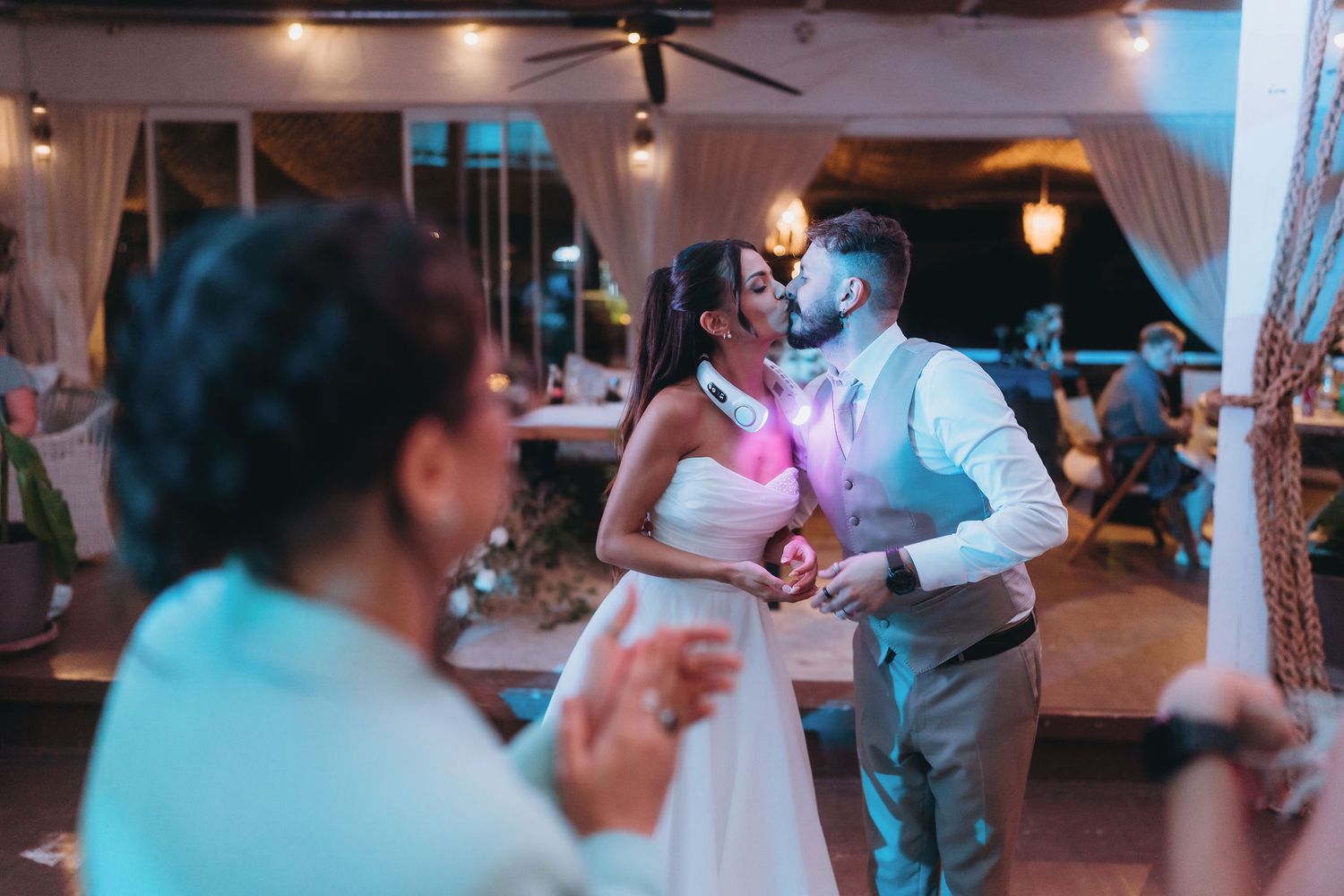 Bride and groom share a romantic first dance kiss at their wedding reception under warm evening lights.