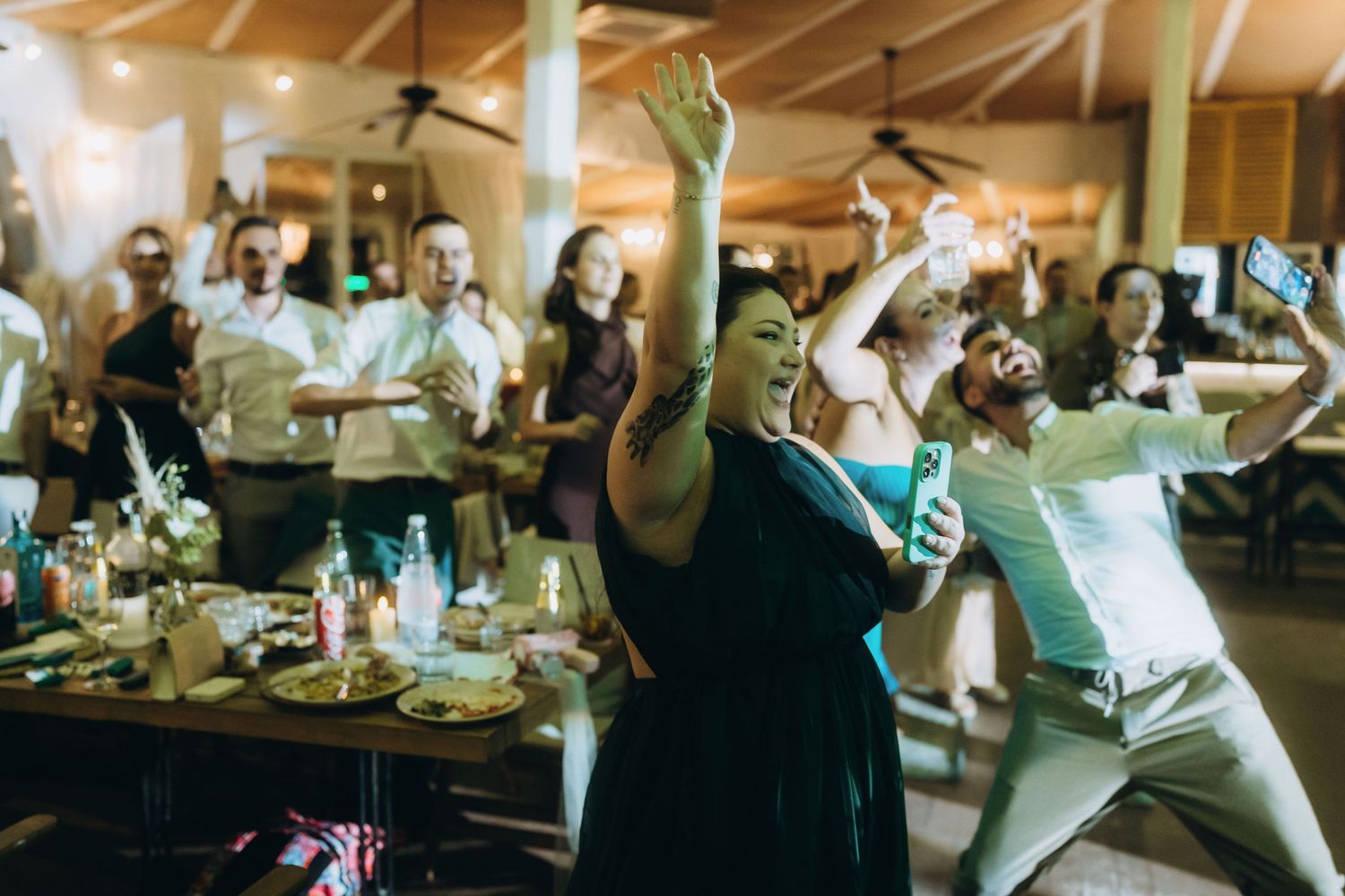 Guests dancing and celebrating at a lively indoor wedding reception party.