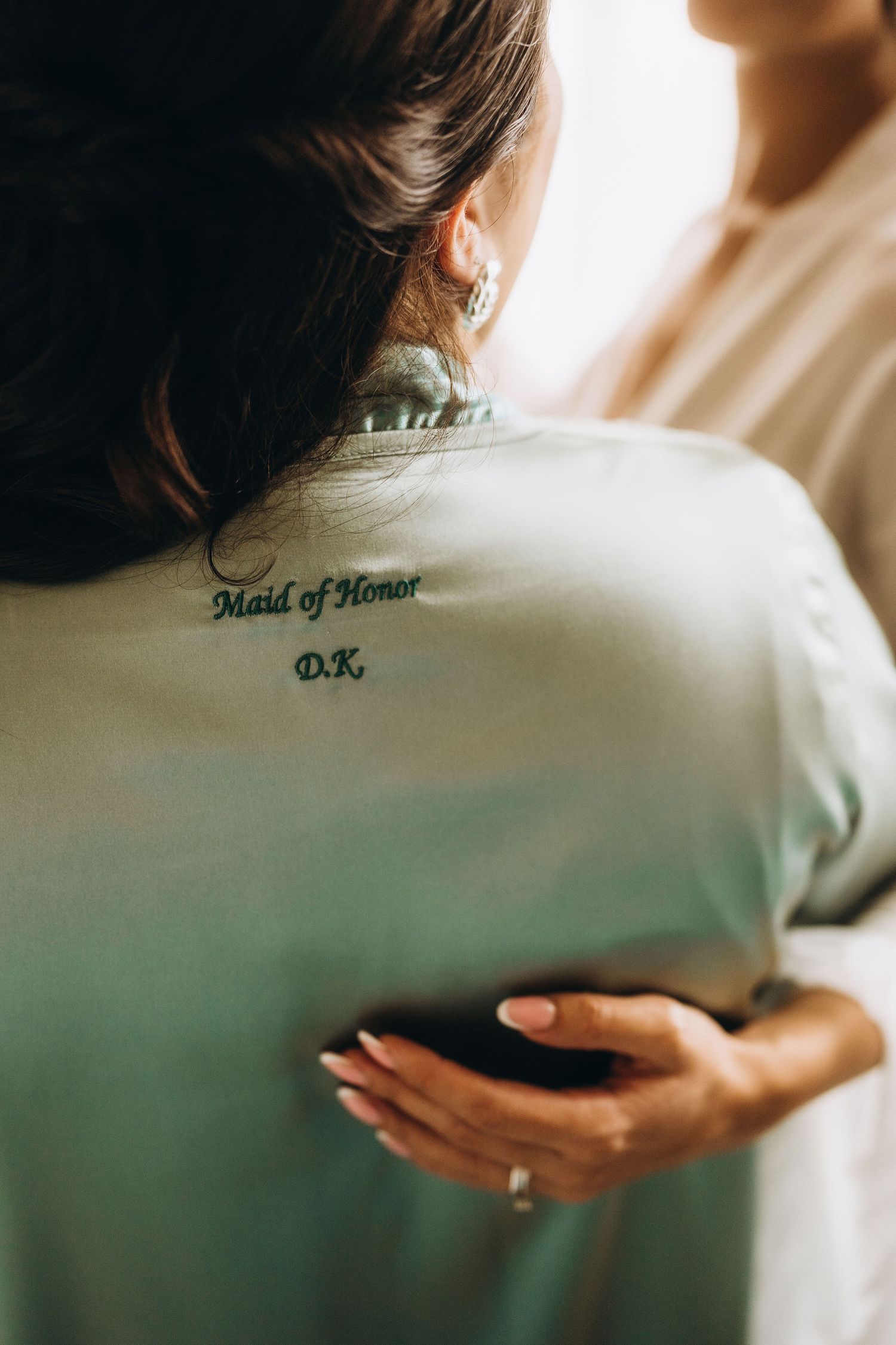 Maid of Honor robe with monogram DK embroidered on back, worn during wedding preparations.