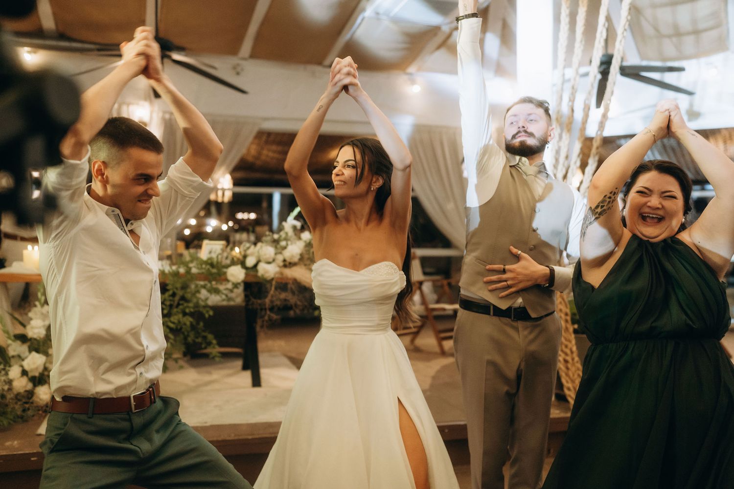 Bride and groom dancing energetically with guests at a festive wedding reception.