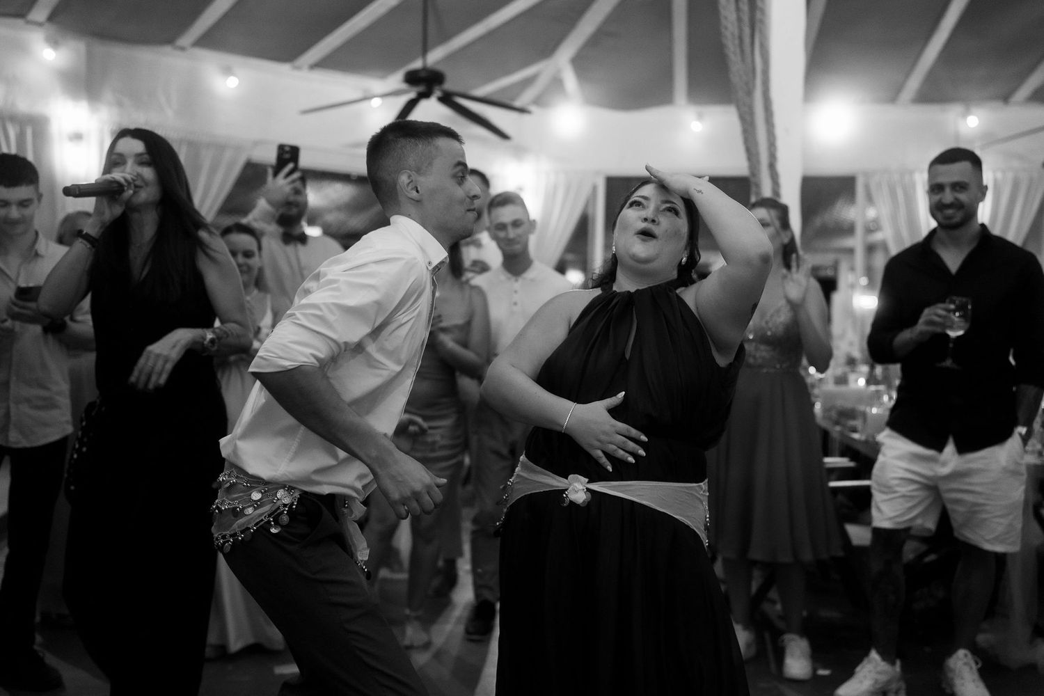 Guests dancing energetically at a wedding reception in black and white photo.