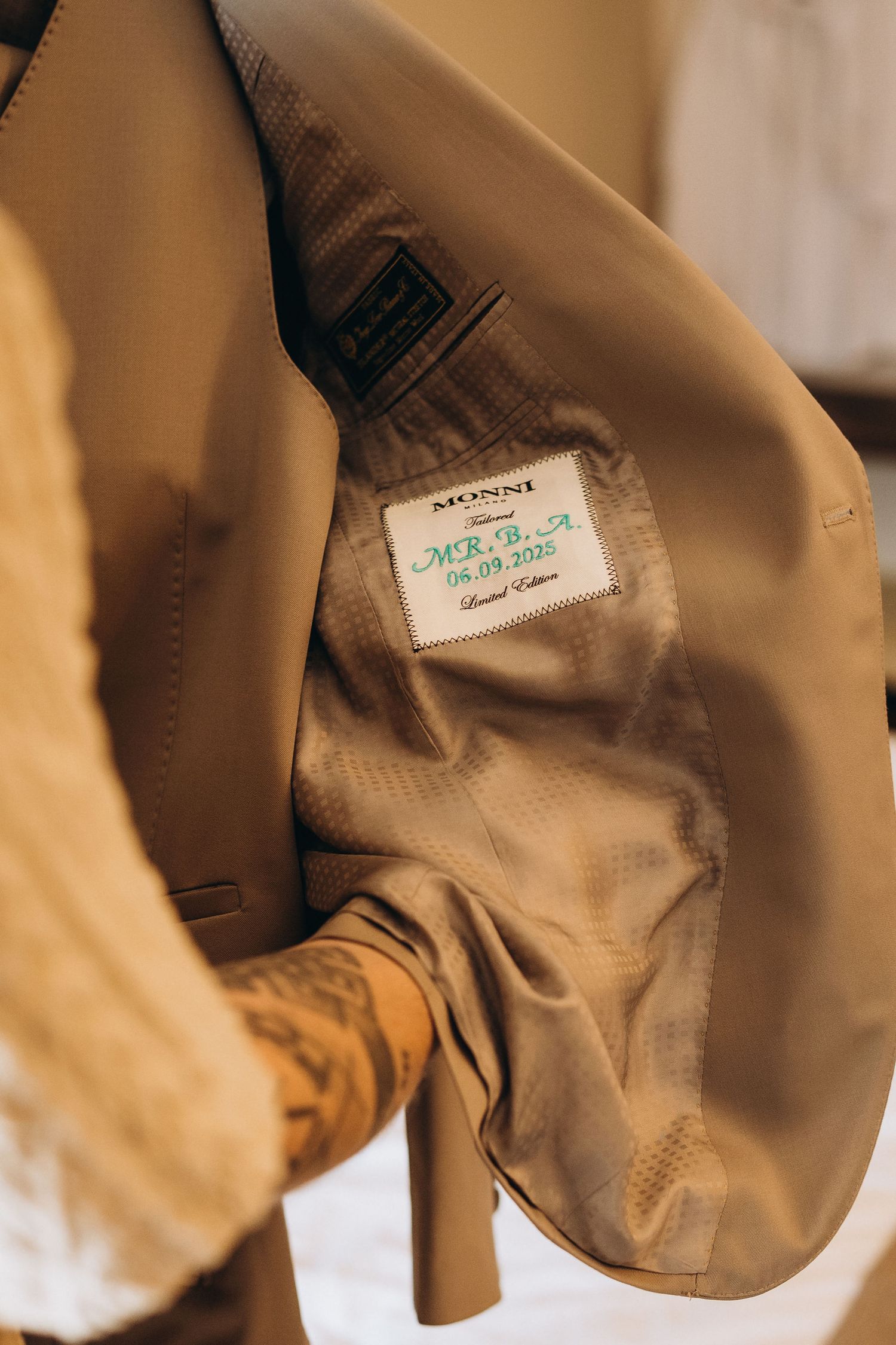 Close-up of a custom MONNI suit jacket lining with a personalized label showing initials and date.