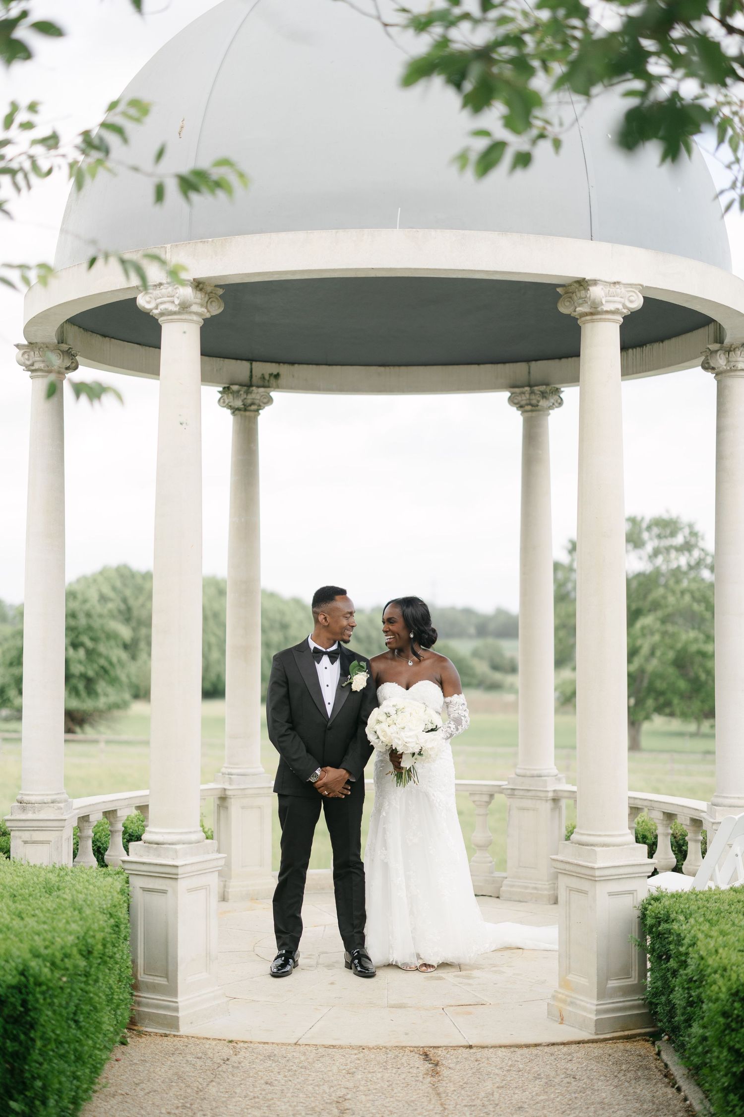 A wedding couple shares joyful moments together on the grounds of an elegant historic mansion.