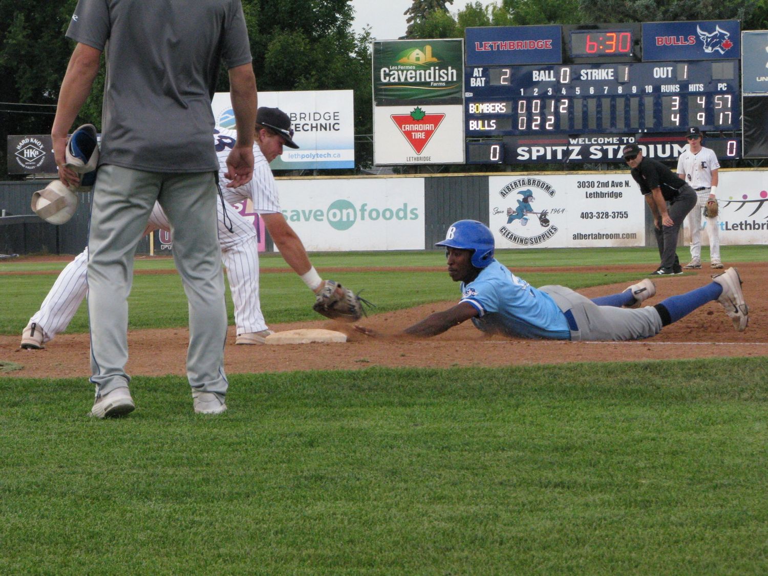 Brooks Bombers (WCBL) player slides into base during a game at Spitz Stadium while fielder attempts to make the tag.