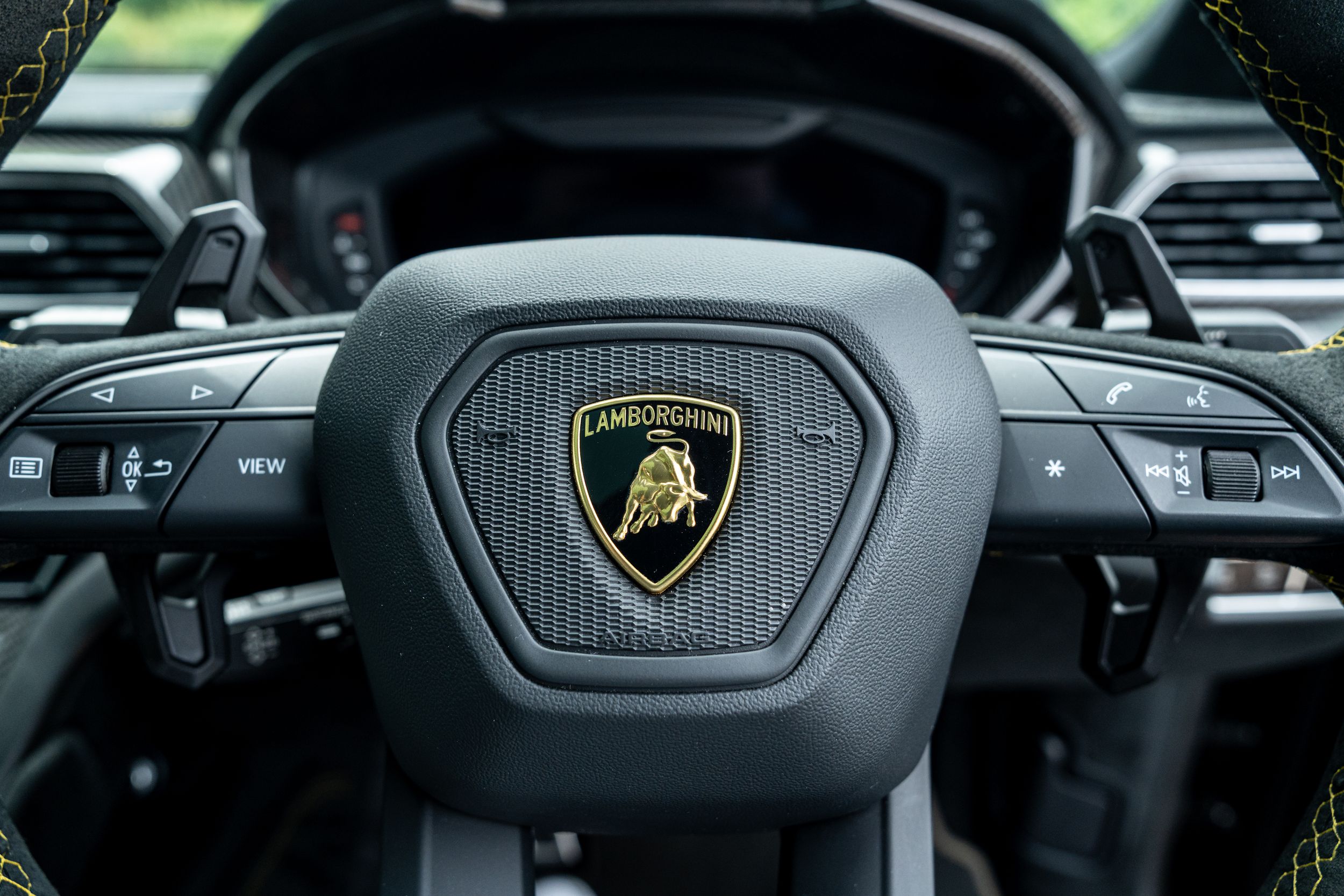 Lamborghini Urus steering wheel center with gold and black bull logo badge detail.
