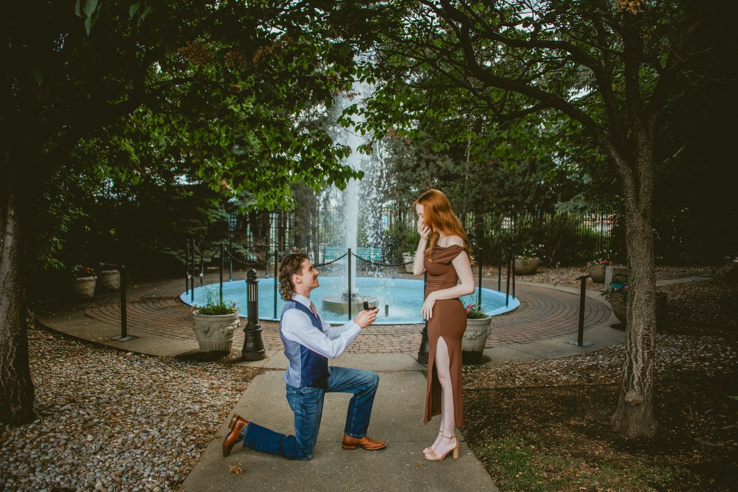 A diamond engagement ring beside a cattle tag reading Marry Me Yes/No on a rustic log outdoors.