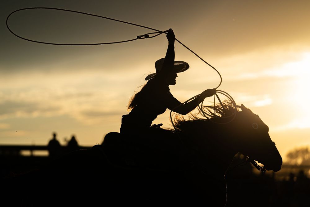 Backlit breakaway roper competing at an amateur event