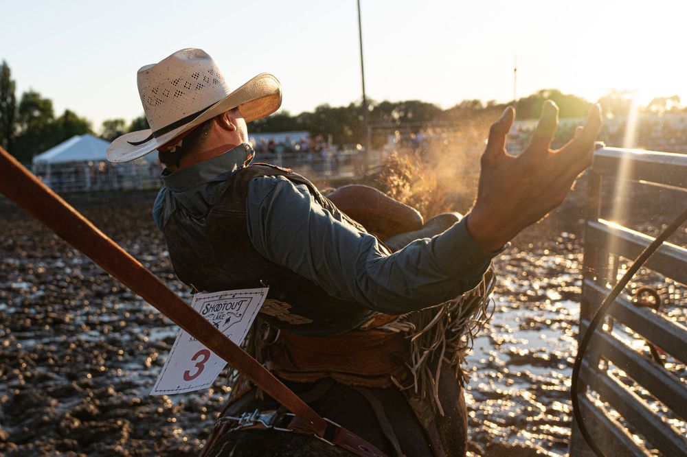 Saddle bronc rider leaving the chutes at an amateur rodeo