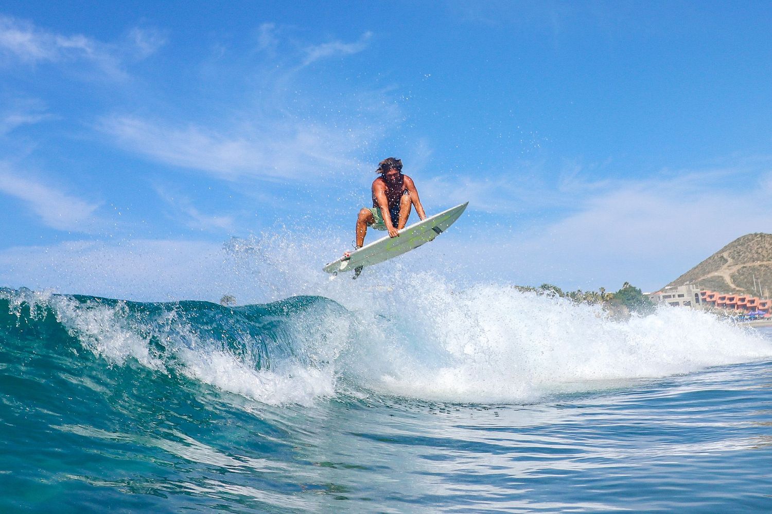 Mexico surf photography of a male surfer catching big air and flying above a wave on his surfboard at Cerritos Beach.