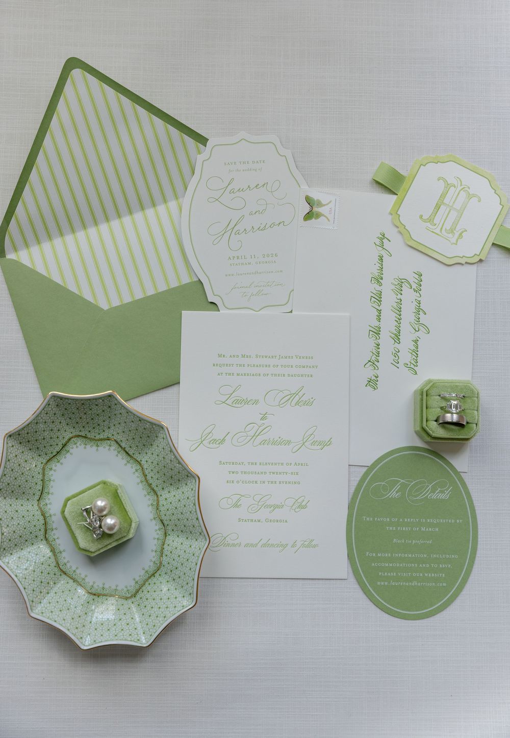 Green and white wedding invitation suite with striped envelope liner, monogram tag, and coordinating details on a light background.
