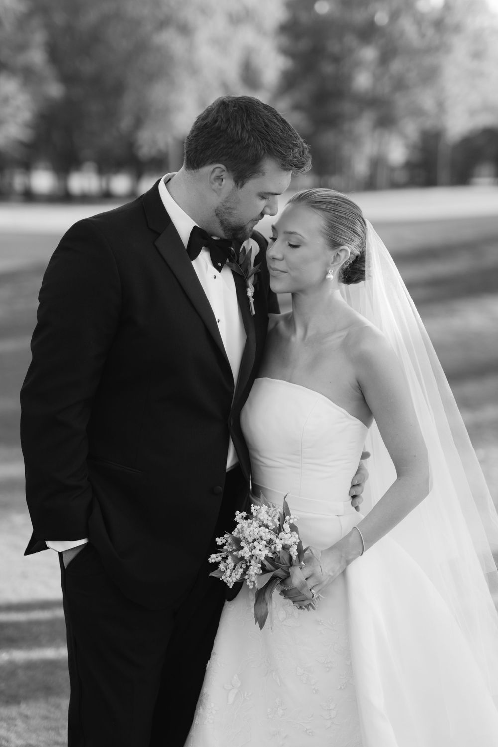 Black and white portrait of bride and groom embracing outdoors on their wedding day.