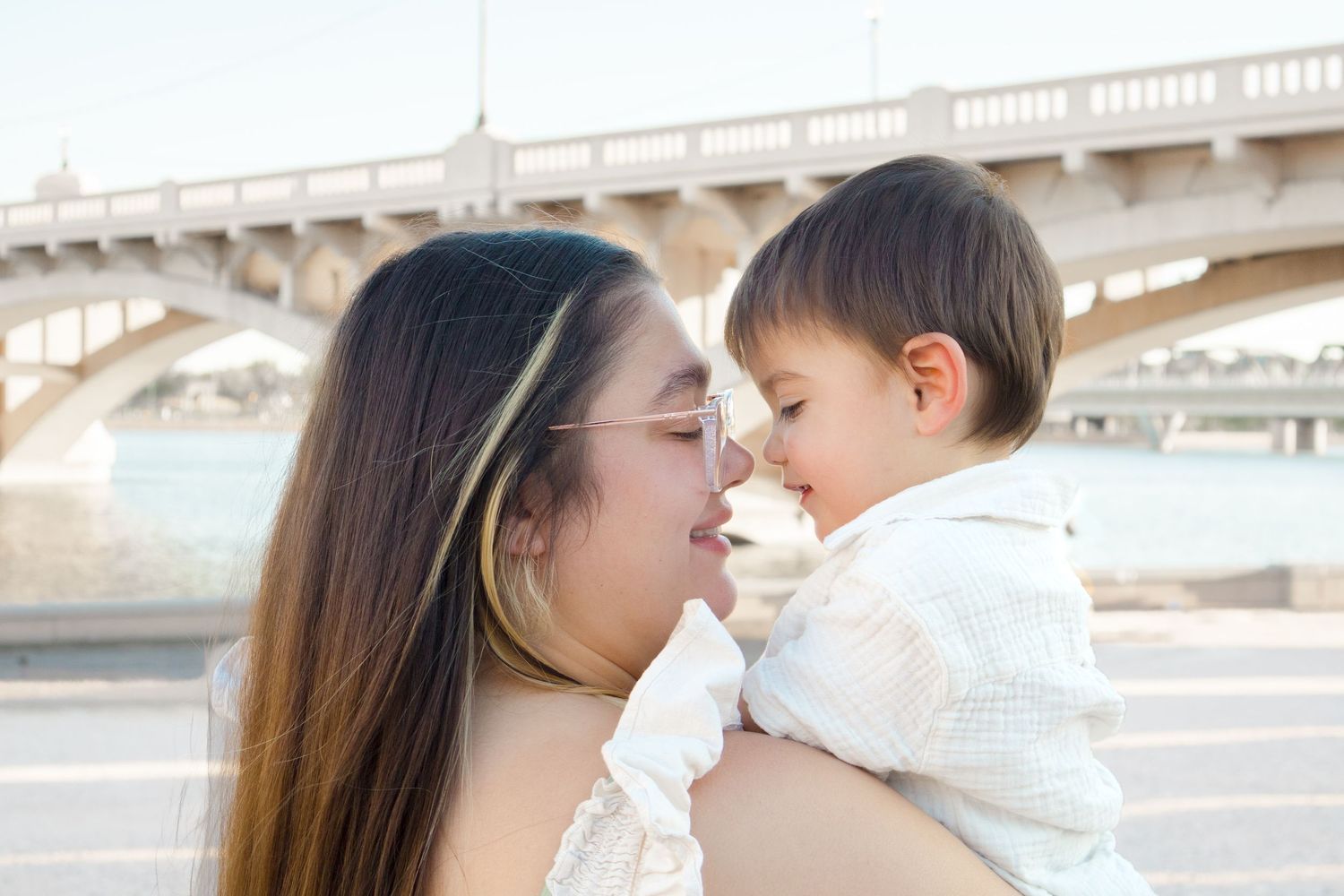 Light and airy motherhood photo of a mom smiling nose to nose with her toddler.