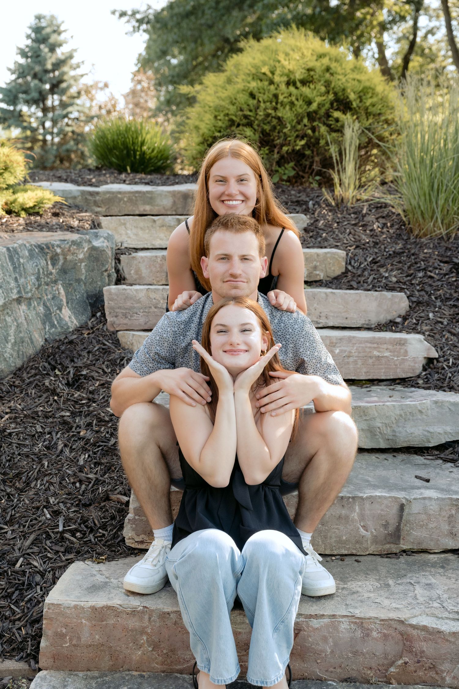 three teenage siblings sitting on steps for silly summer family portrait on lake wissota in chippewa falls wi