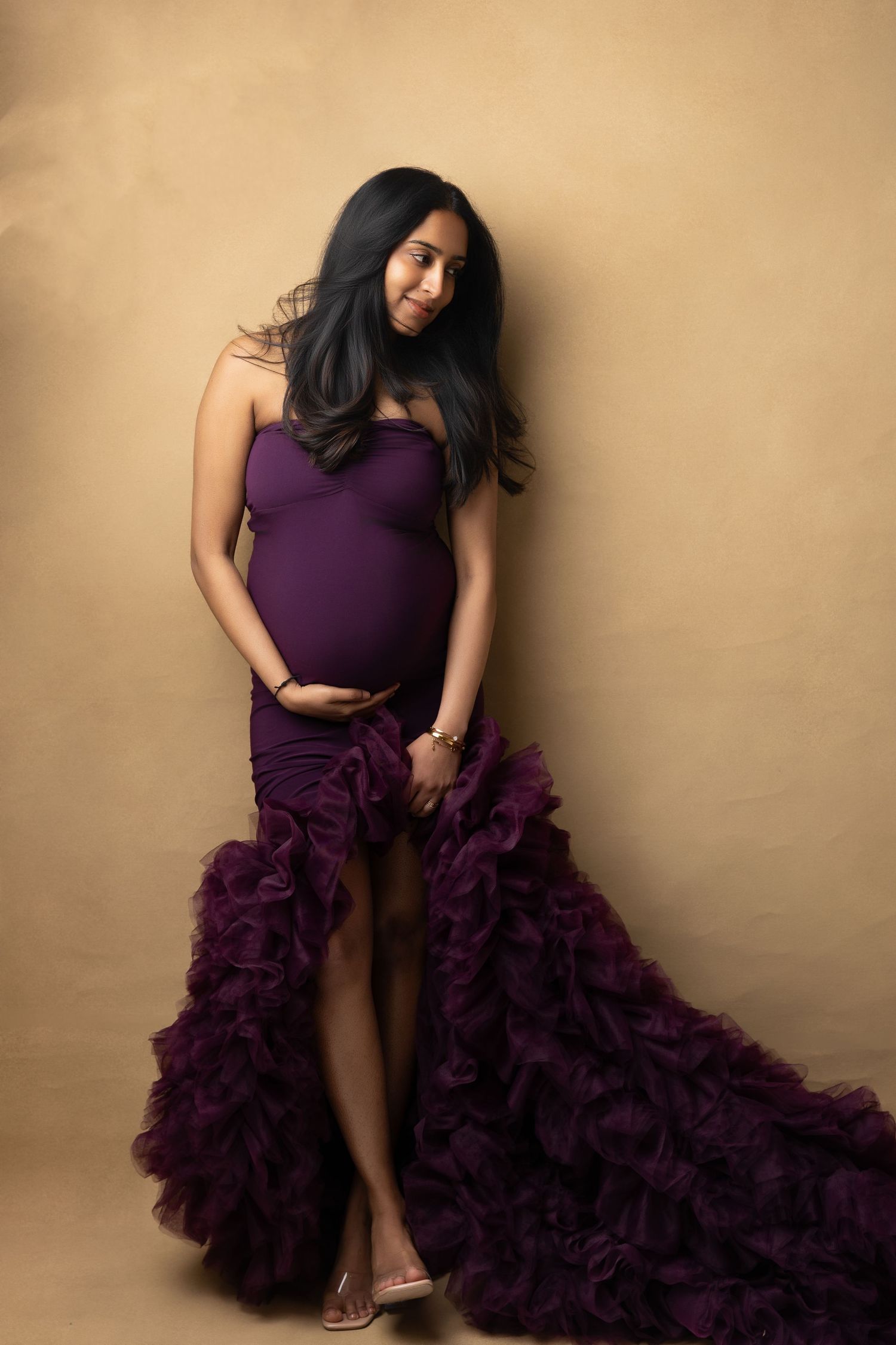 Young girl kisses sleeping newborn baby in a white wicker pram during a studio photo session.