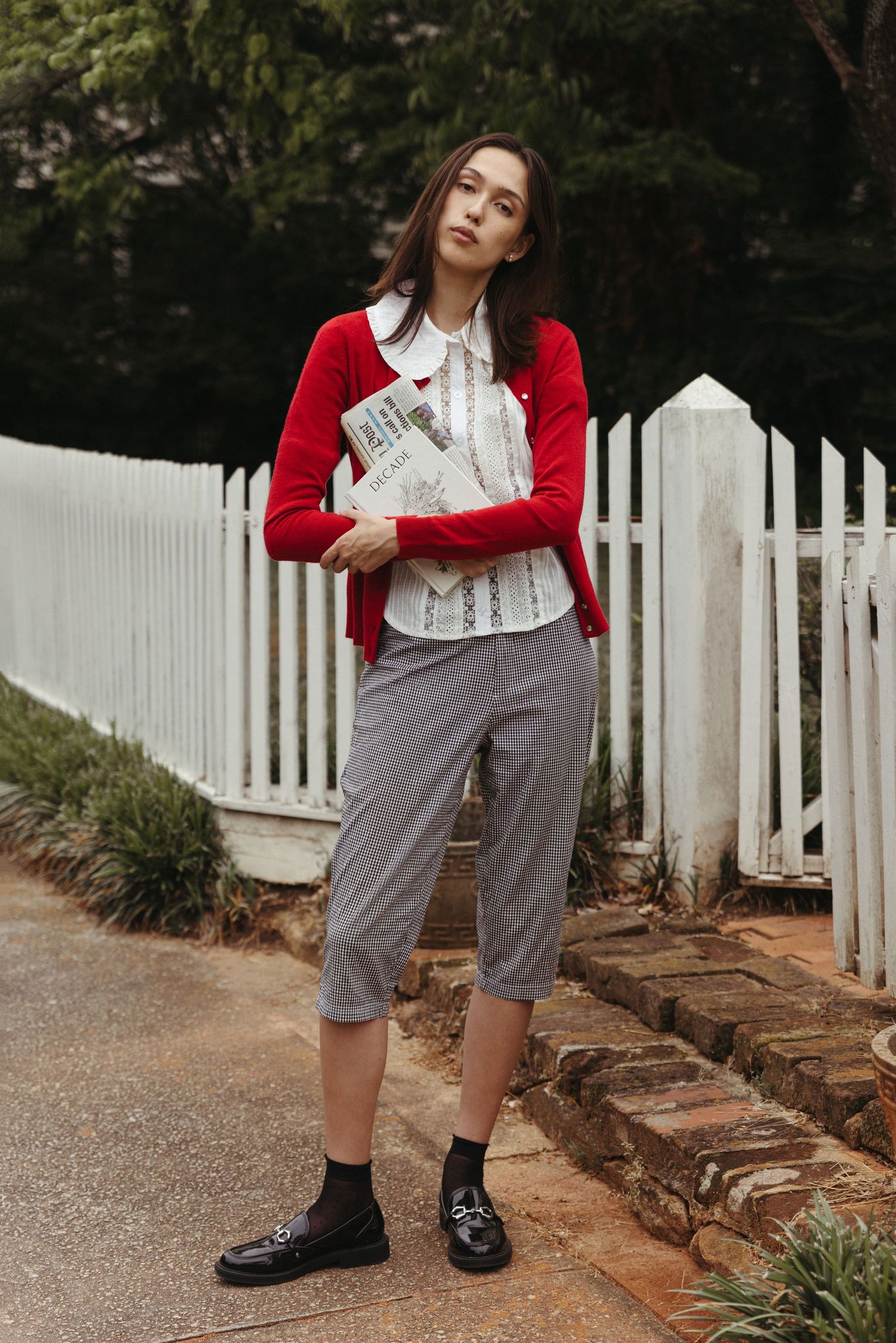 Editorial model wearing vintage red sweater and holding books and newspapers, Atlanta fashion photography