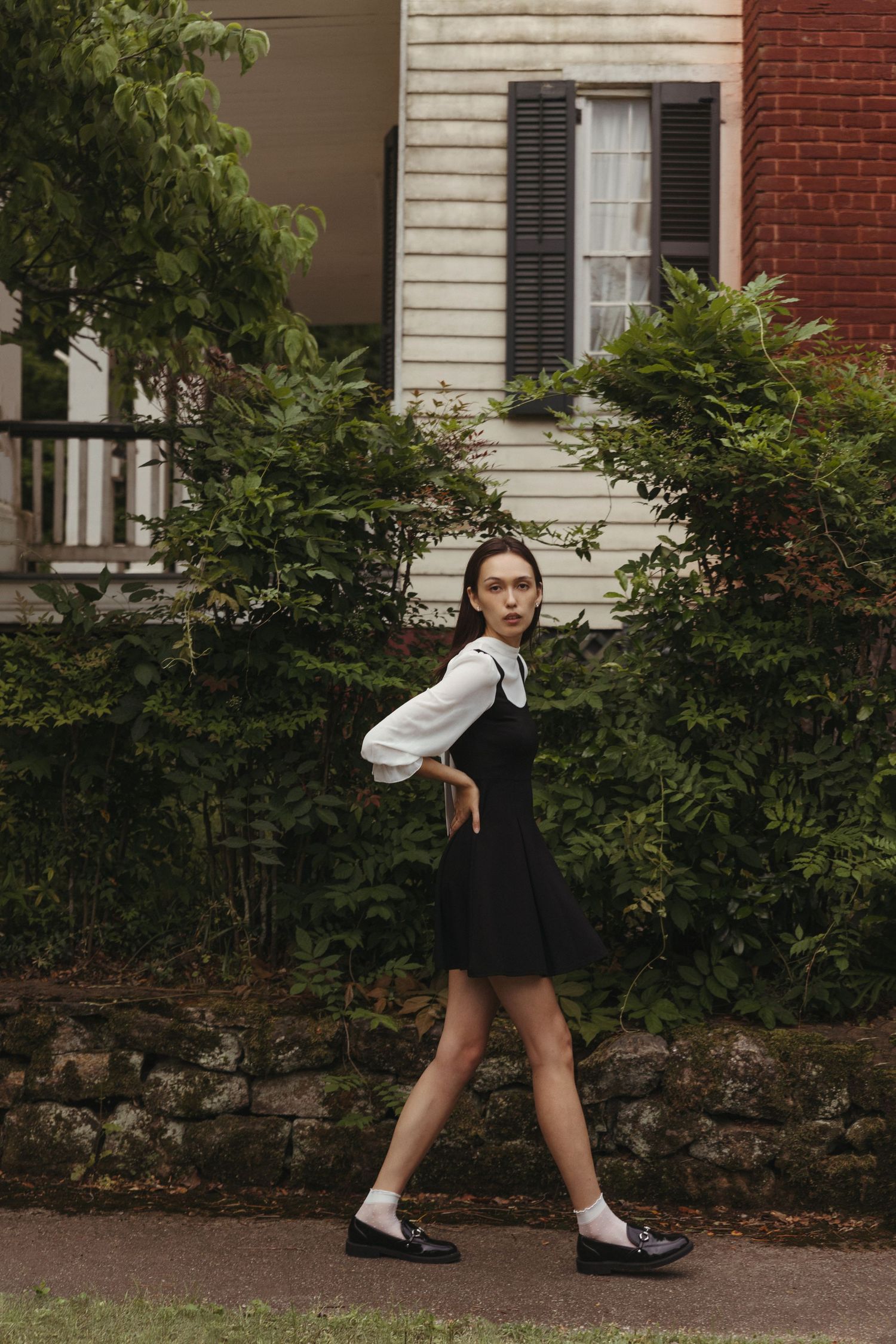 Editorial model walking in historic neighborhood wearing black and white pinafore dress and loafers, Atlanta fashion photography
