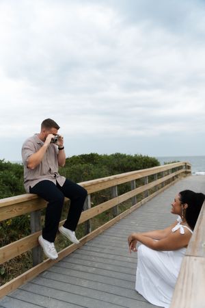 Man sitting on wooden boardwalk railing photographing Located in Connecticut at Harkness State Park