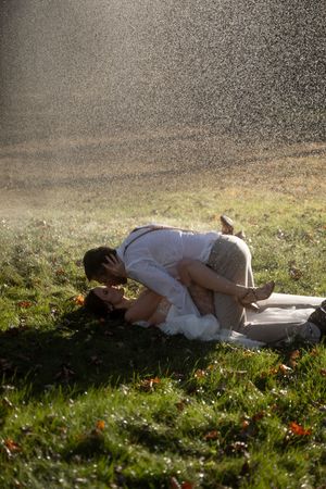A couple sharing a romantic kiss on green grass in the rain session in Westerly Rhode Island.