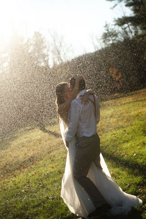 Bride and groom kissing in a sparkling water spray during outdoor rain session in Westerly Rhode Island.