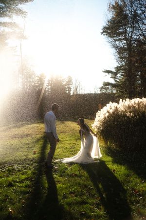 Bride and groom holding hands in golden sunlight rain session in Westerly Rhode Island.