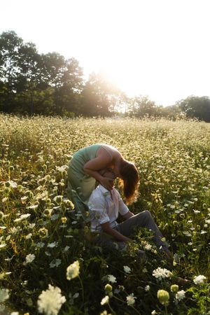 Couple sharing a romantic moment in a sunlit wildflower meadow, surrounded by white blooms and trees. Flower field located in Connecticut