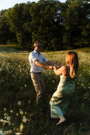 Couple dancing in a sunny wildflower meadow, woman in green dress, Flower field located in Connecticut