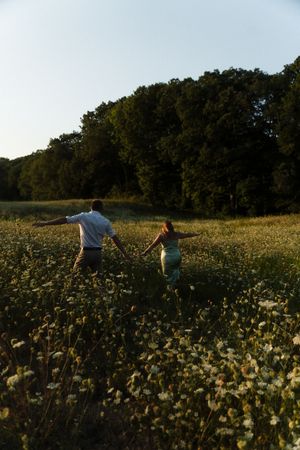 Couple holding hands running through a wildflower meadow at golden hour Flower field located in Connecticut
