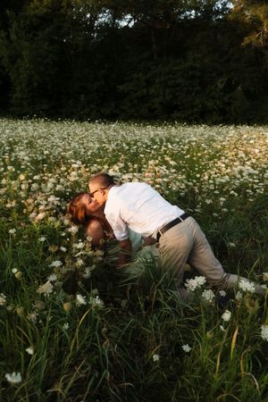 Couple sharing a romantic kiss in a field of white wildflowers at golden hour Flower field located in Connecticut