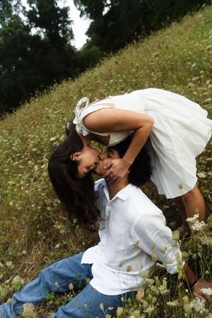 Two children in white outfits share a tender moment in a wildflower meadow, Flower field located in Connecticut