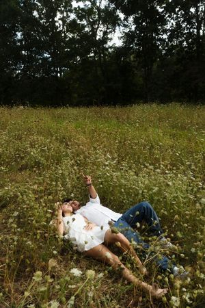 Couple lying together in a wildflower meadow, surrounded by lush green trees. Flower field located in Connecticut
