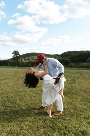 Couple dancing outdoors in a green field, rolling hills and cloudy sky backdrop. Candlelight Farms located in Connecticut