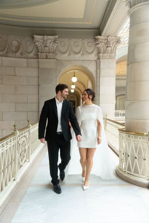 Couple in formal attire walking through an elegant marble building with arched ceilings. Hartford city hall located in Connecticut
