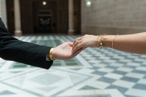Close-up of bride and groom holding hands, on a marble floor.couples engagement session at the Hartford City Hall