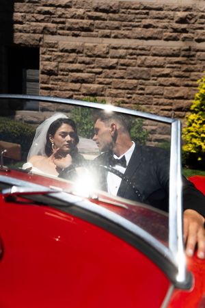 Bride and groom sitting together in a classic red convertible car on their wedding day.Ocean Cliff in Newport Rhode Island