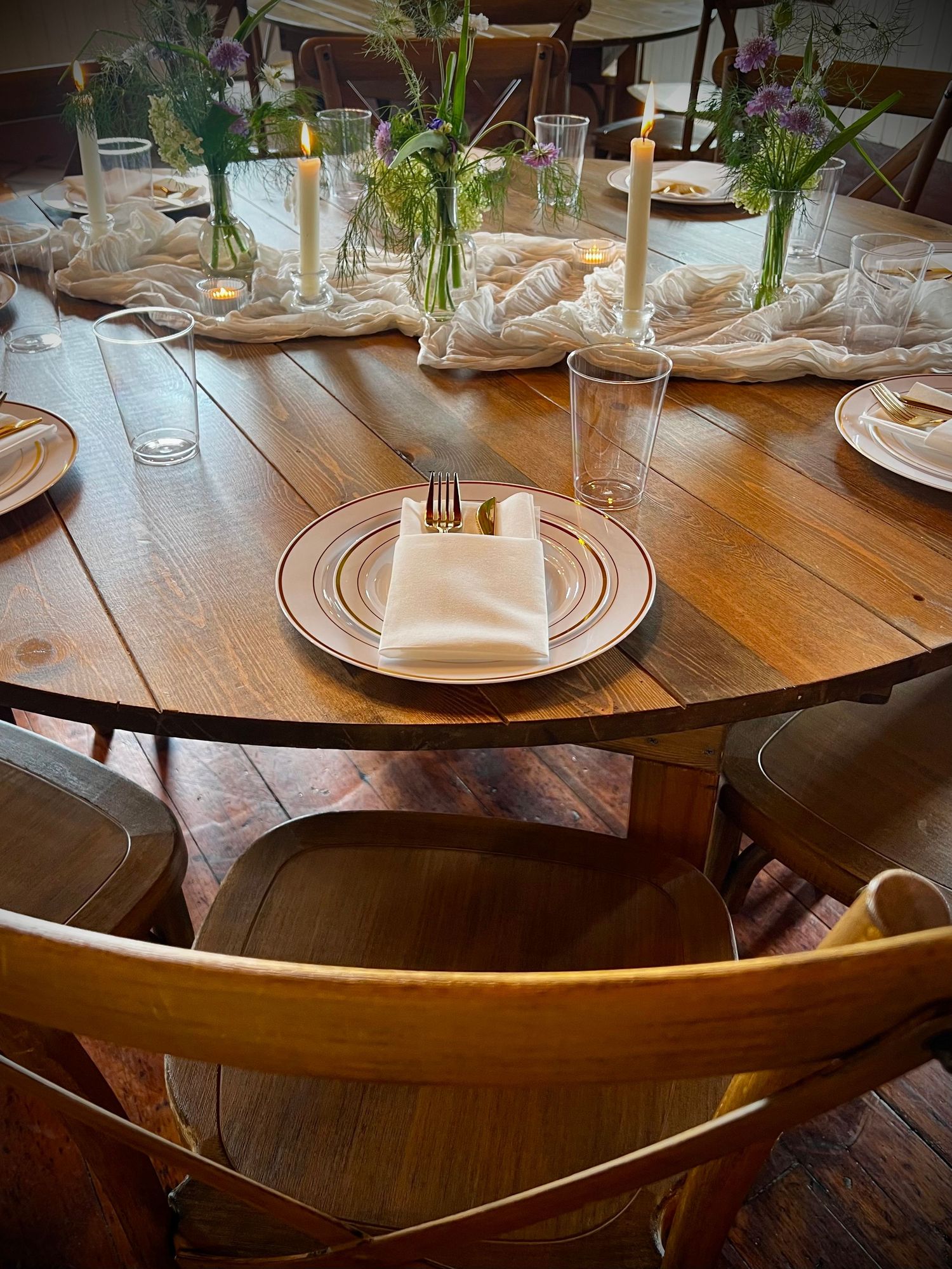 Elegant farmhouse table set with gold chargers, crystal glasses, sage napkins, and white floral centerpiece for a formal event.
