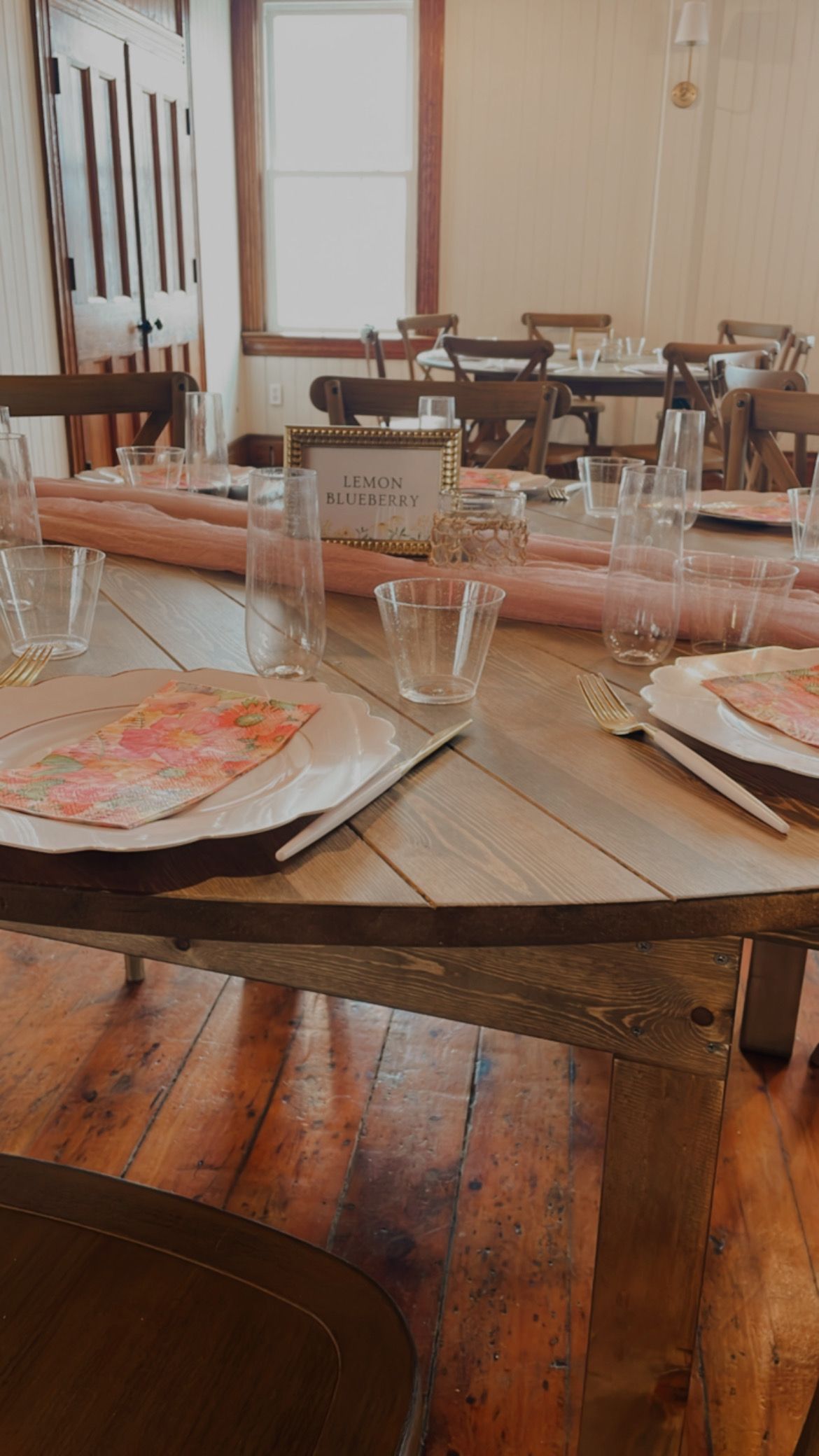 Elegant farmhouse table set with gold chargers, crystal glasses, sage napkins, and white floral centerpiece for a formal event.