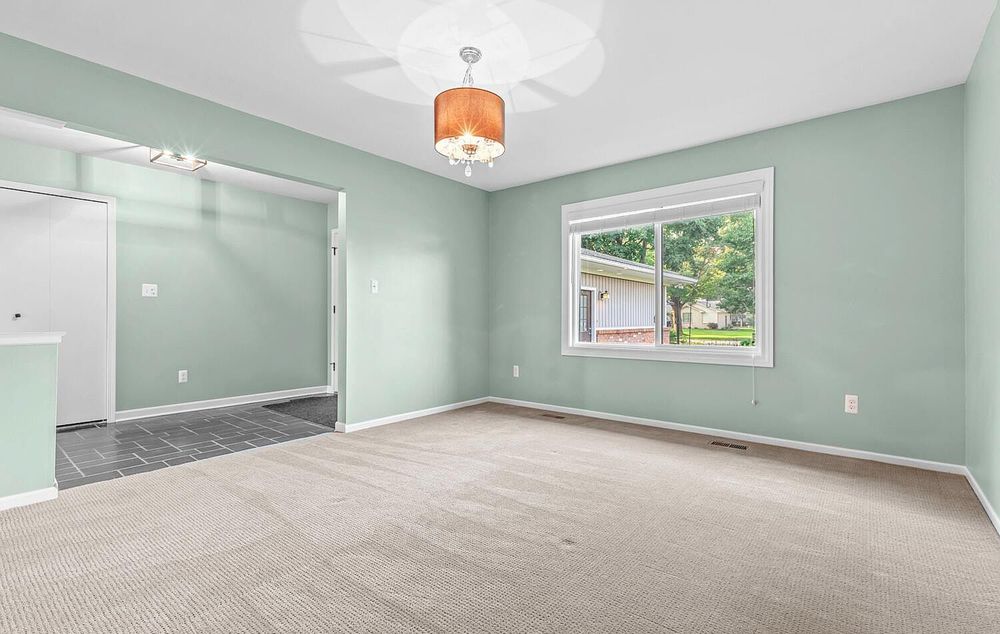 Bedroom with mint green walls, beige carpet, ceiling light fixture, and large window.