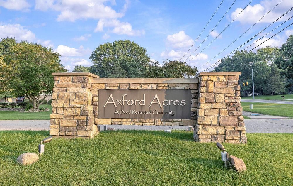 Stone monument entrance sign for Axford Acres community surrounded by trees and landscaping.