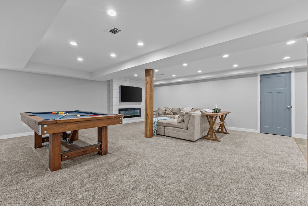 Spacious finished basement with pool table, carpeted floors, recessed lighting, fireplace, and cozy seating area.