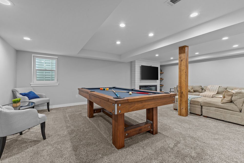 Finished basement recreation room featuring a pool table, sectional sofa, fireplace, and recessed lighting.