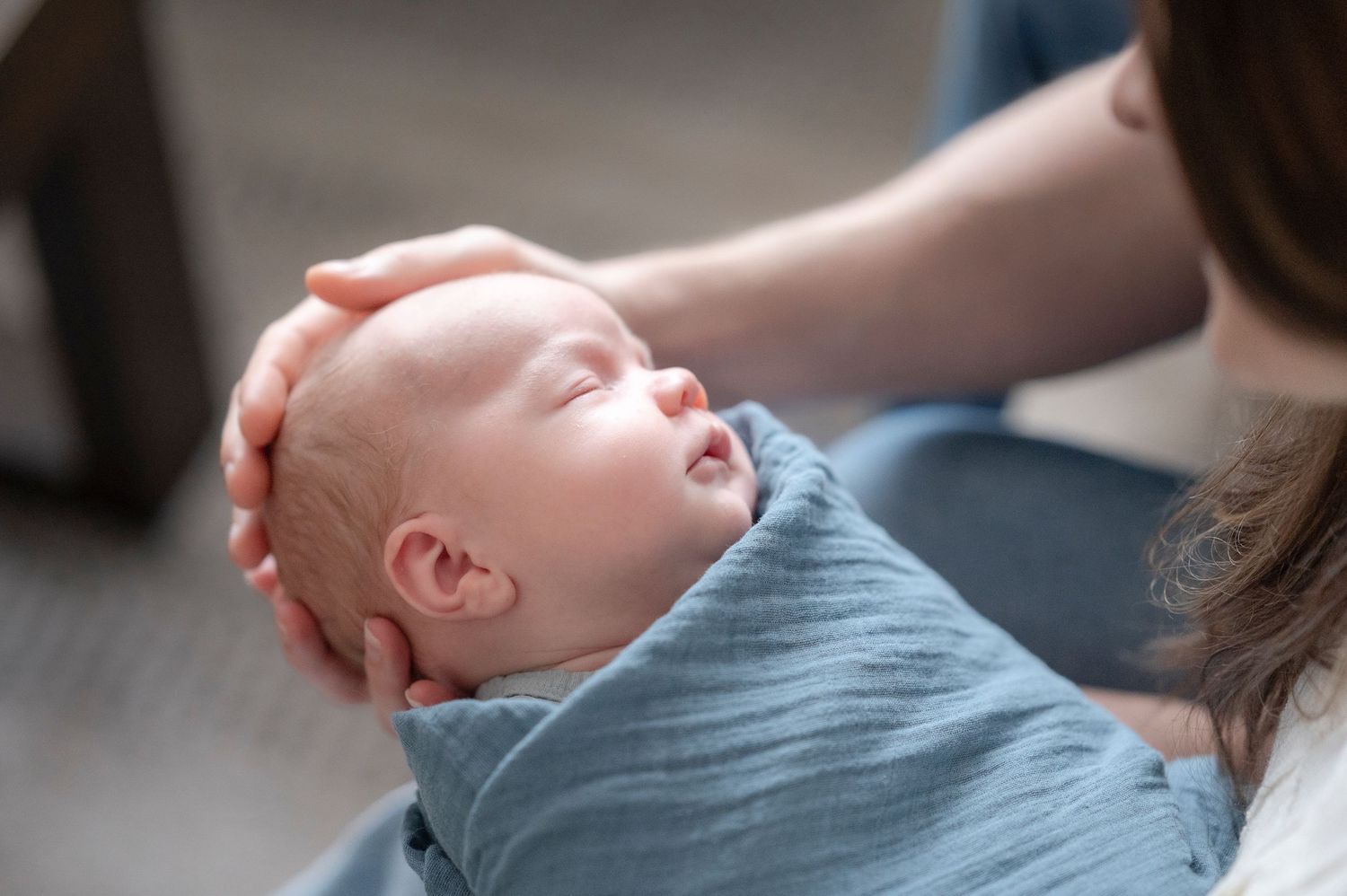 close up detail shot of little baby being cradled by his mom and dad in their home while he sleeps