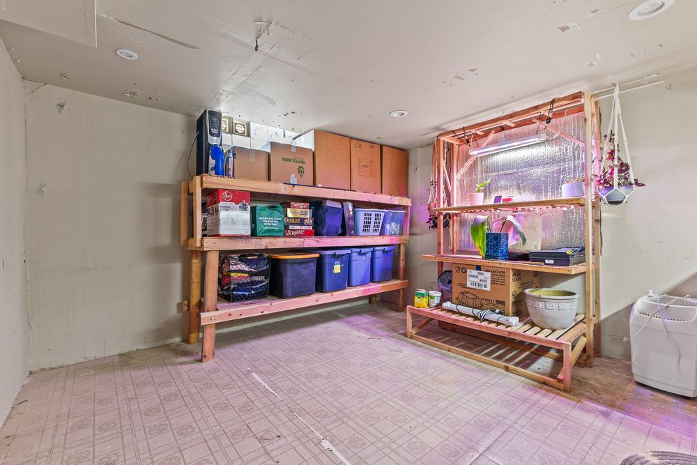 Unfinished basement utility room with wooden storage shelves holding colorful bins and boxes.