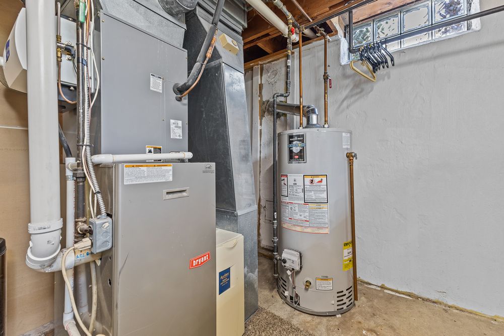 Utility room with gas furnace, water heater, and electrical panel in a home basement.
