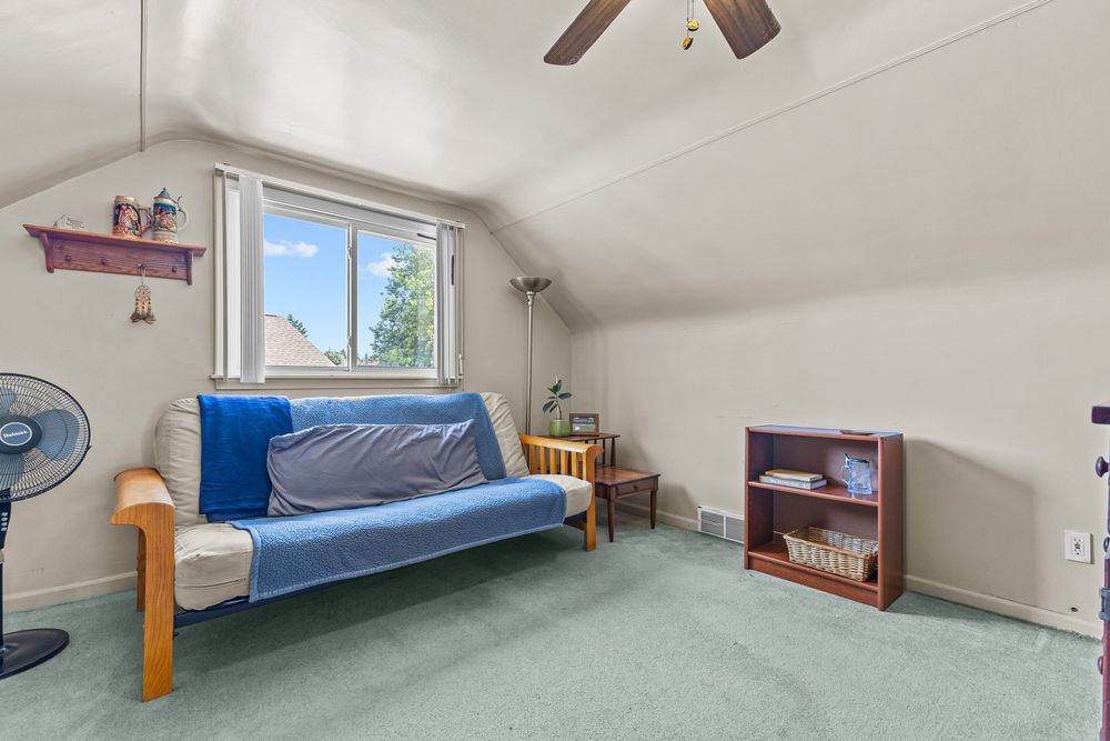Attic bonus room with vaulted ceiling, carpet, futon, ceiling fan, and natural light.