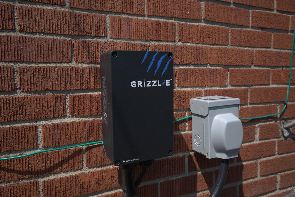 Grizzle EV charger mounted on exterior brick wall for electric vehicle charging.