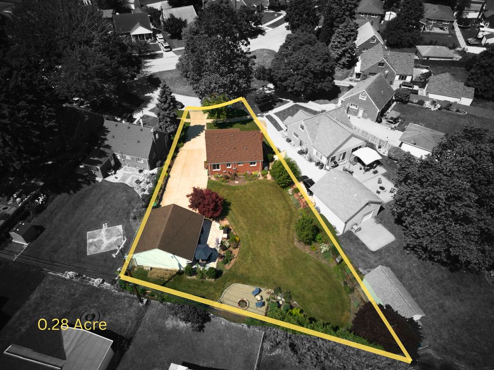 Aerial view of 0.28-acre residential property with lush green lawn and mature trees.